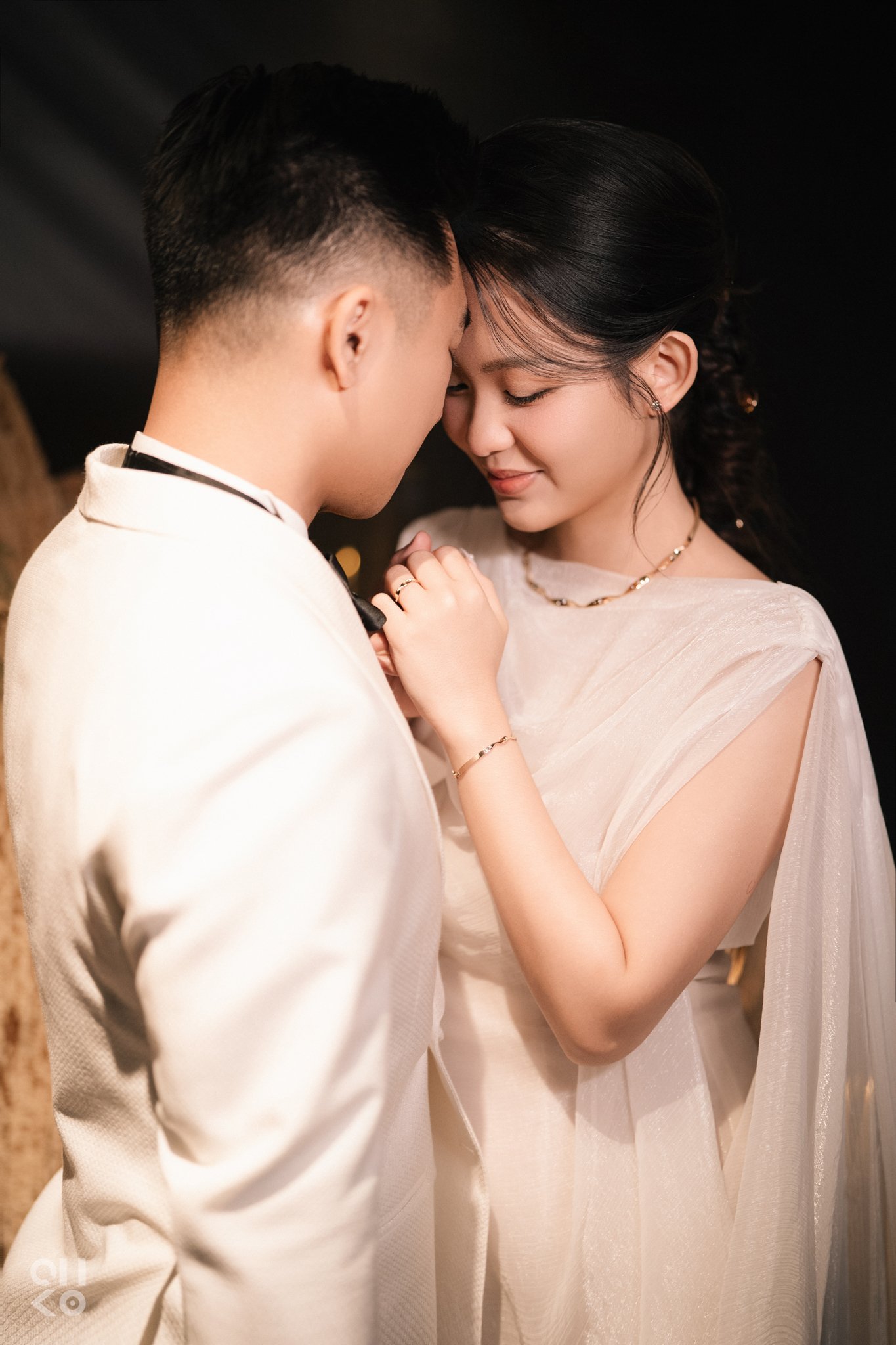 Bride and groom leaning forehead to forehead in candlelight